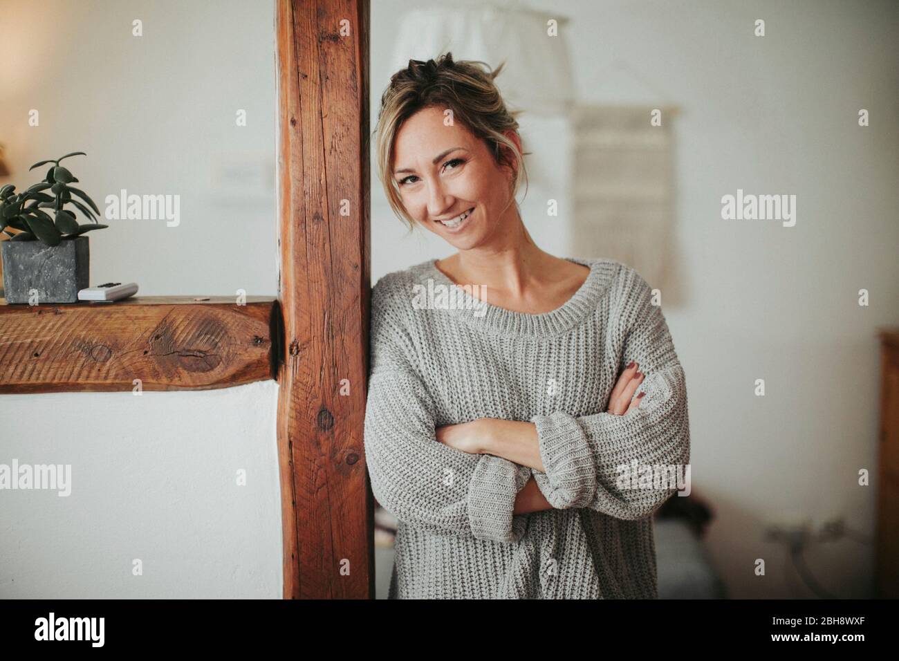 junge Frau in ihrer Wohnung, Arme verschränkt, lächeln, Halbporträt Stock Photo
