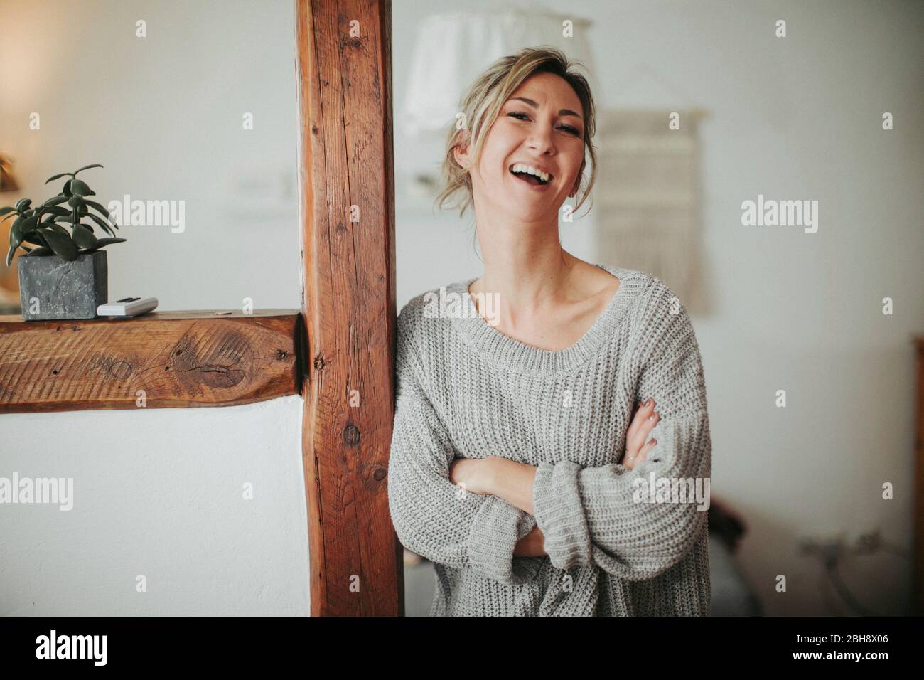 junge Frau in ihrer Wohnung, Arme verschränkt, lachen, Halbporträt Stock Photo