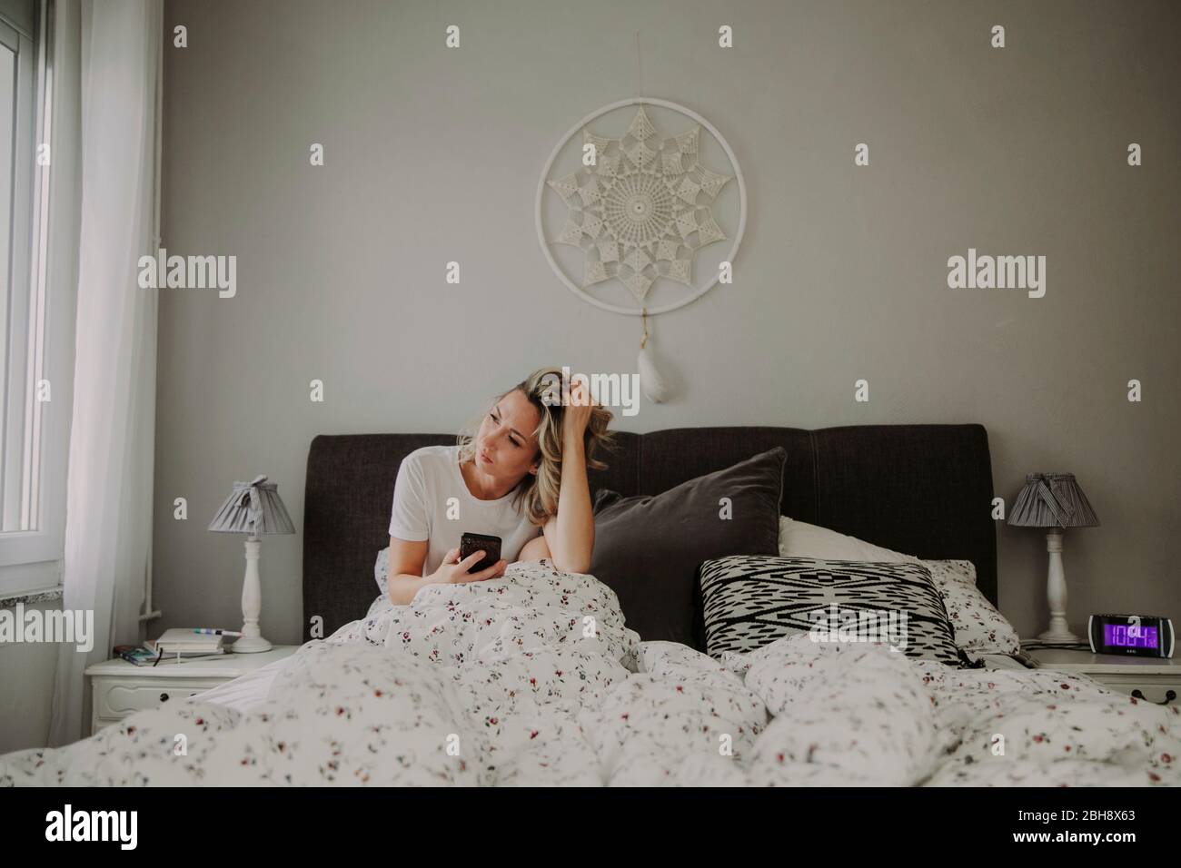 Frau mit Smartphone im Bett Stock Photo
