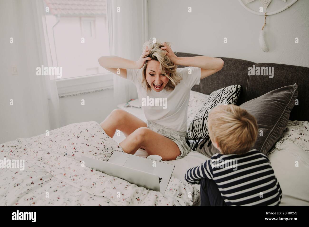 Mutter und Sohn im Bett, Frau blickt entsetzt auf ihr Laptop Stock Photo -  Alamy