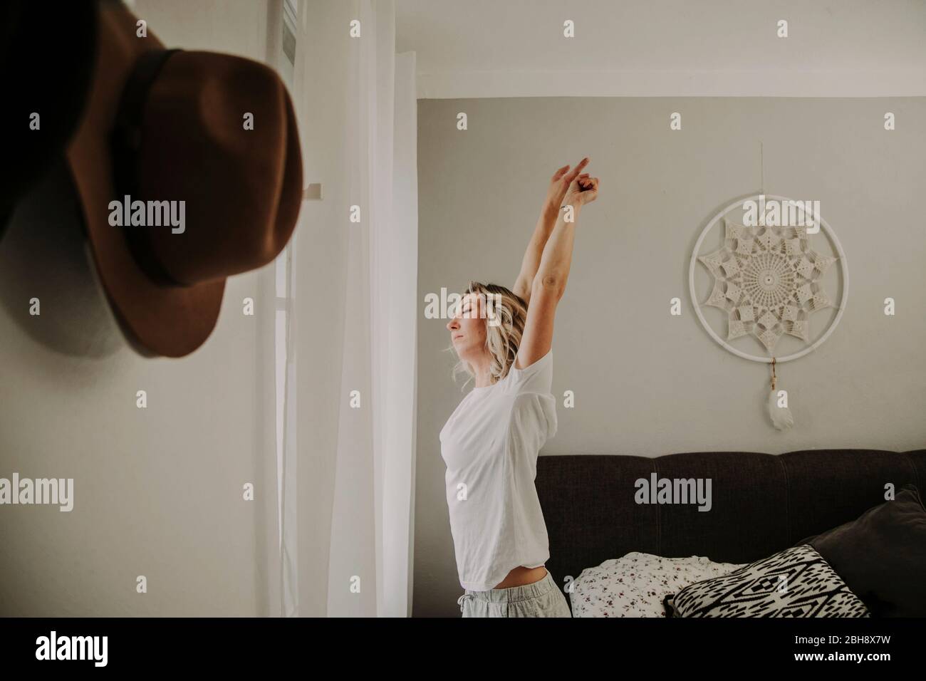 Woman stands at the bedroom window and stretches Stock Photo
