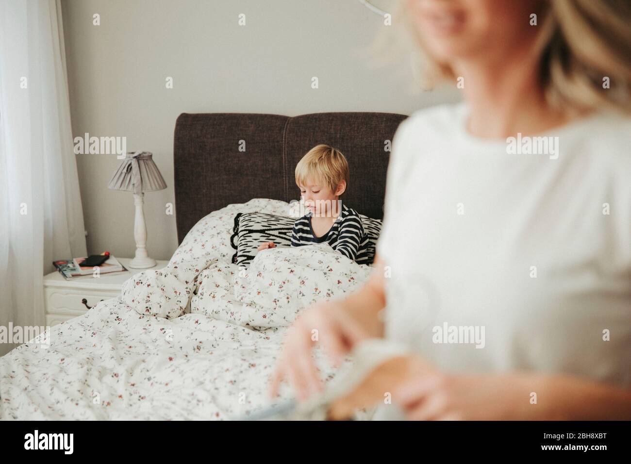 Morgens, Frau kleidet sich an, Sohn liegt in ihrem Bett Stock Photo