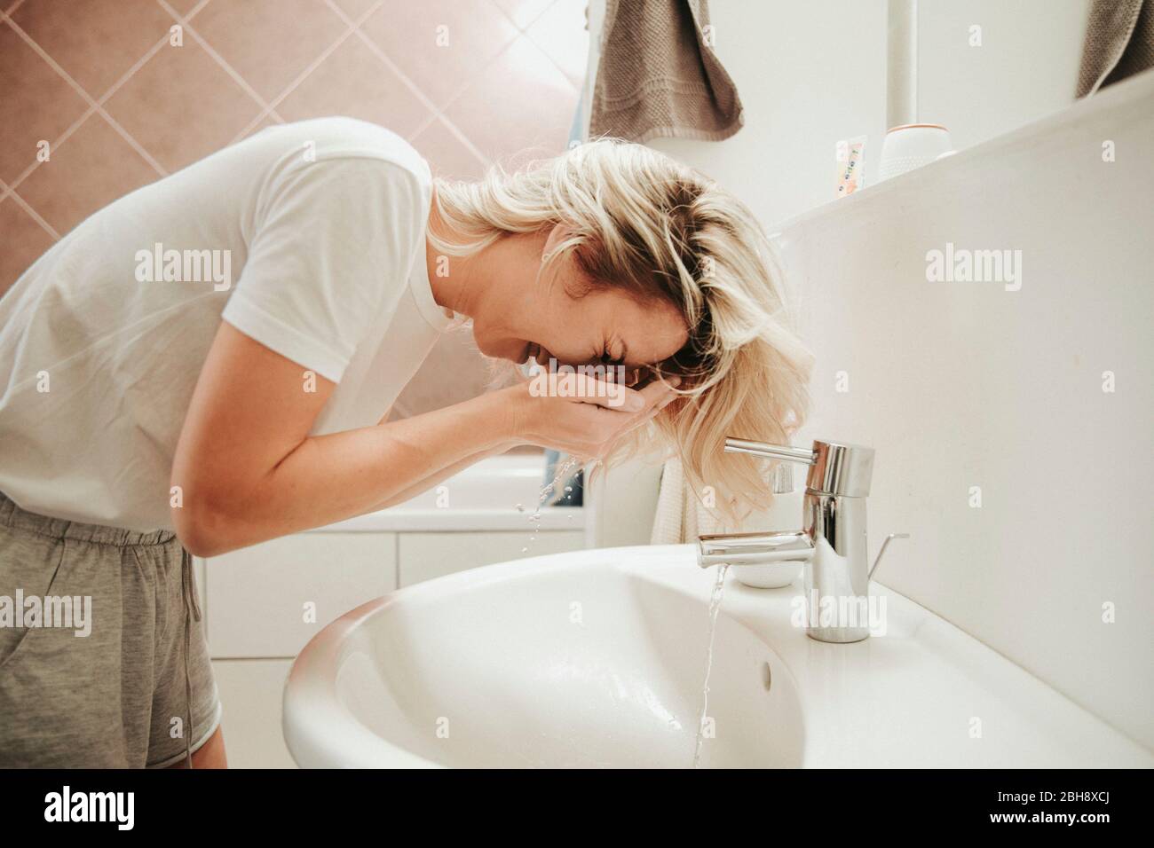 Frau im Badezimmer, wäscht ihr Gesicht Stock Photo