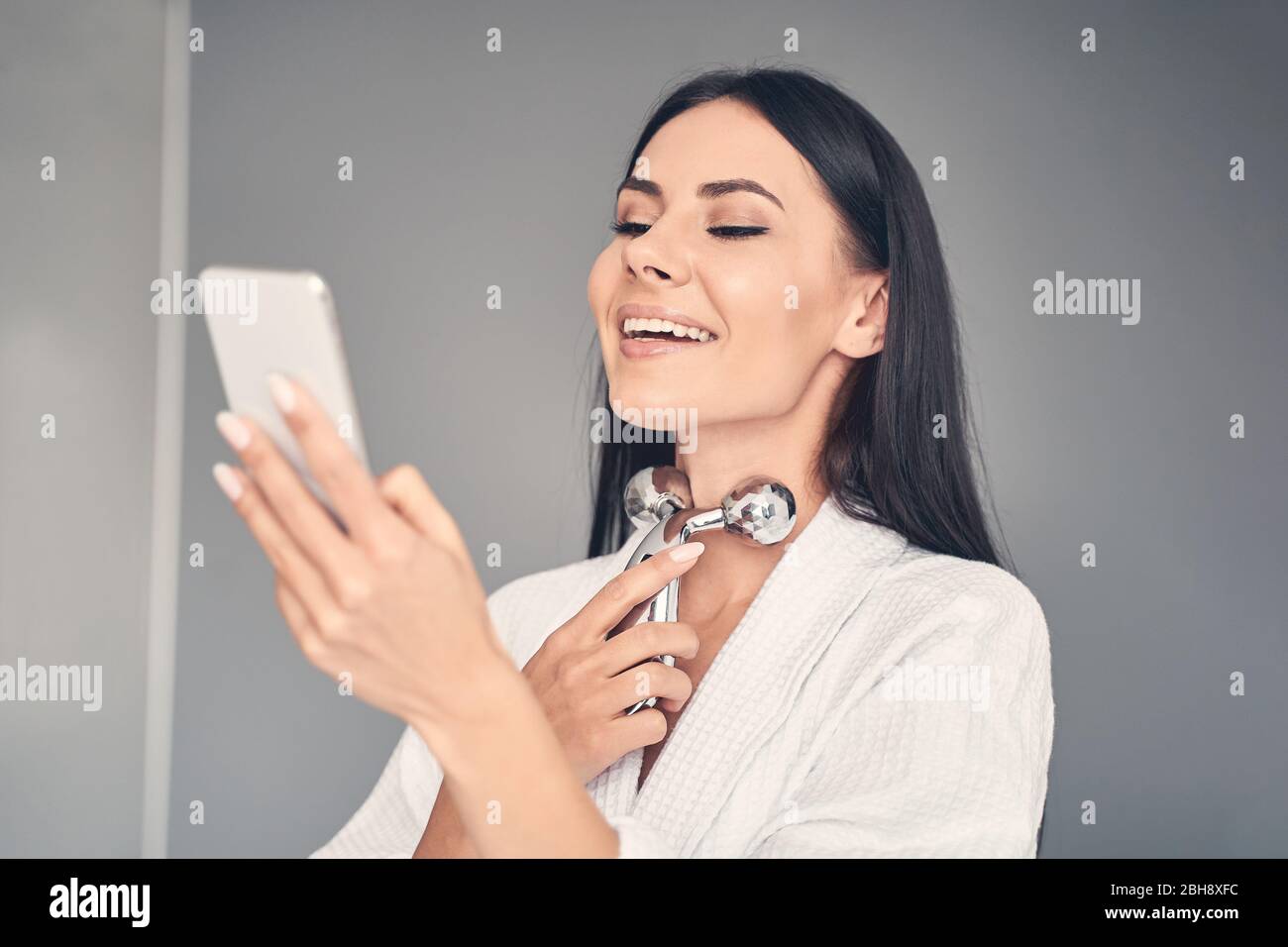 Girl with a smartphone massaging her neck Stock Photo - Alamy