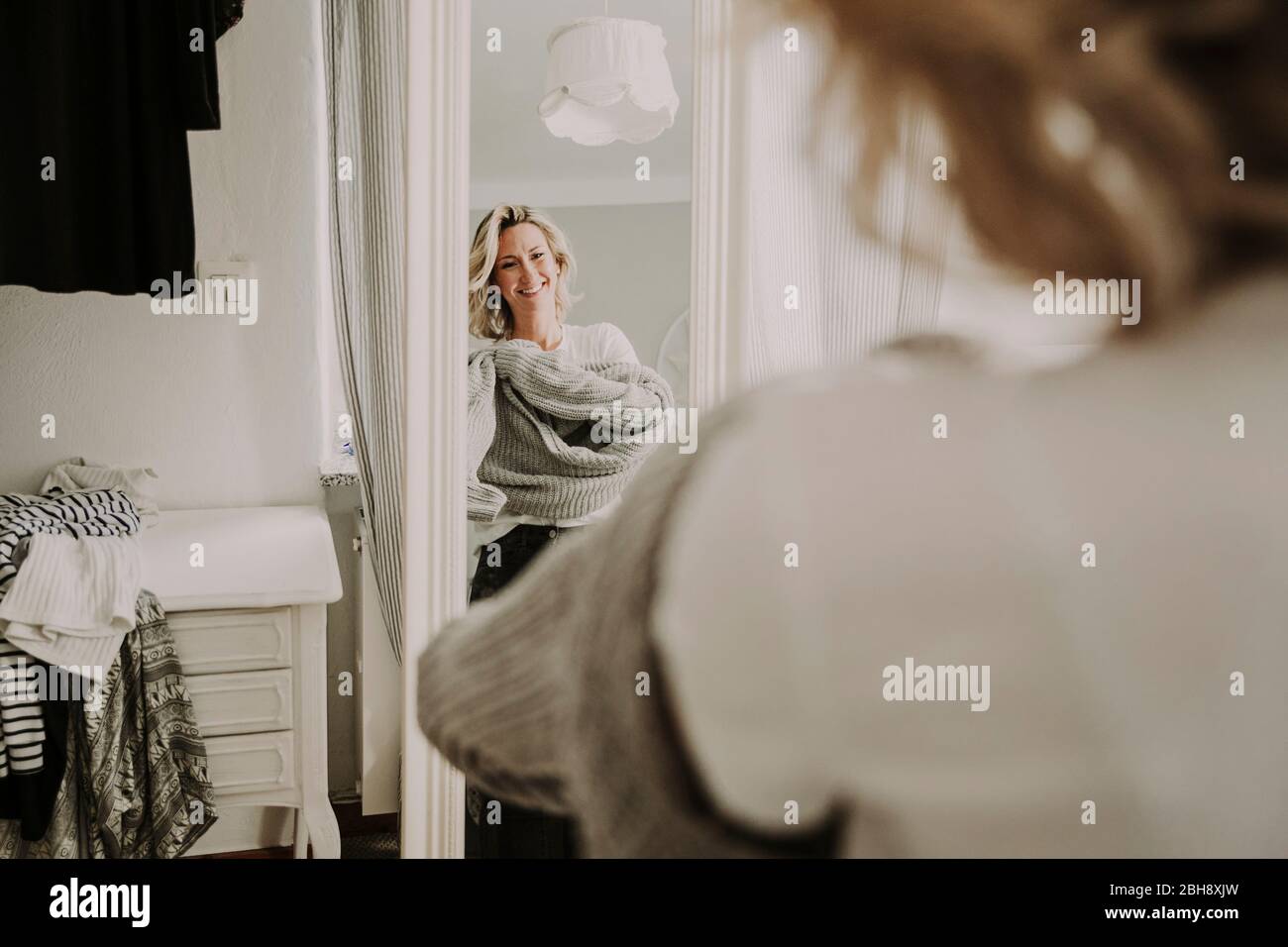 Frau steht vor dem Spiegel, kleidet sich an Stock Photo