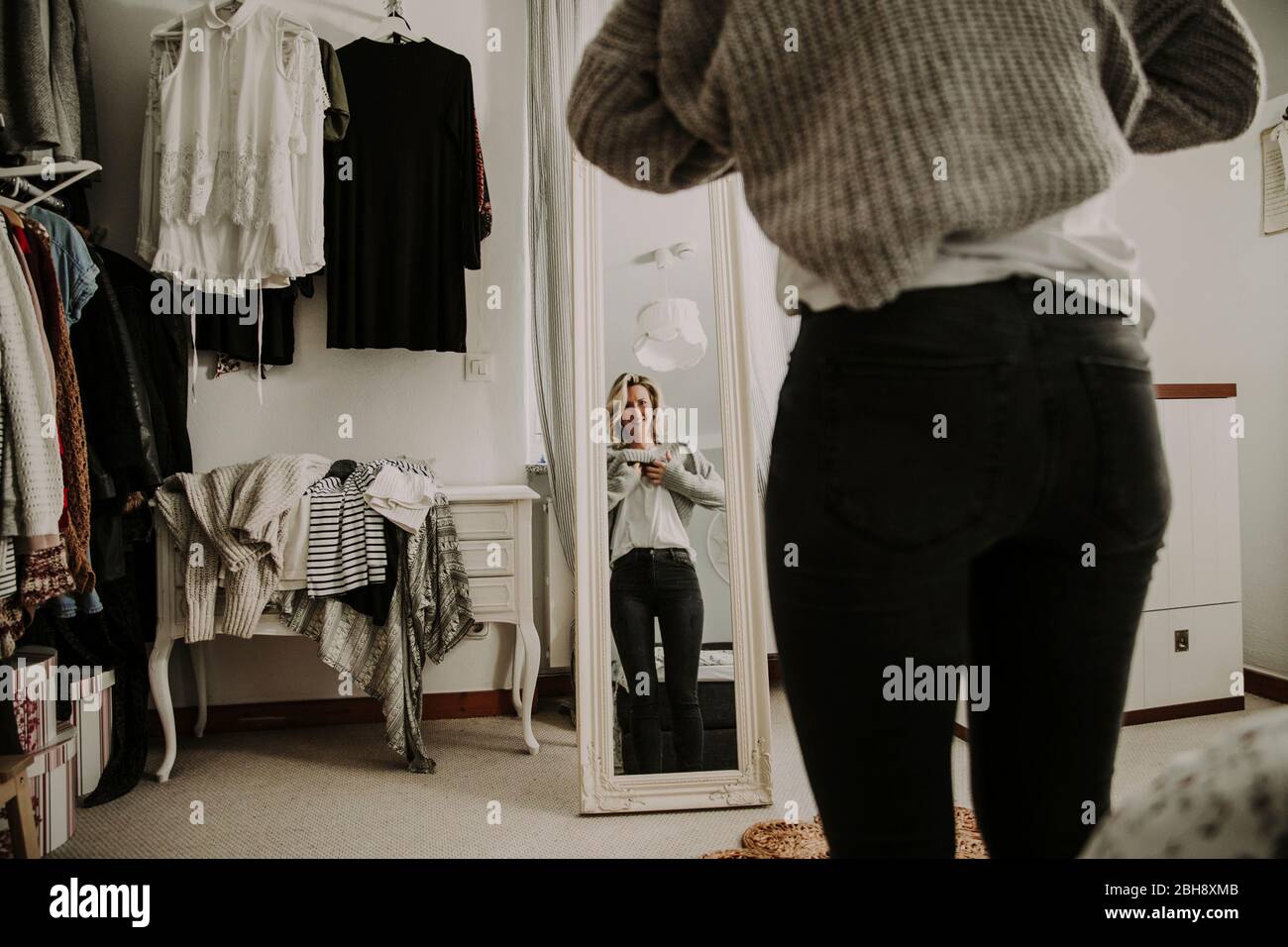 Woman stands in front of the mirror, dresses Stock Photo
