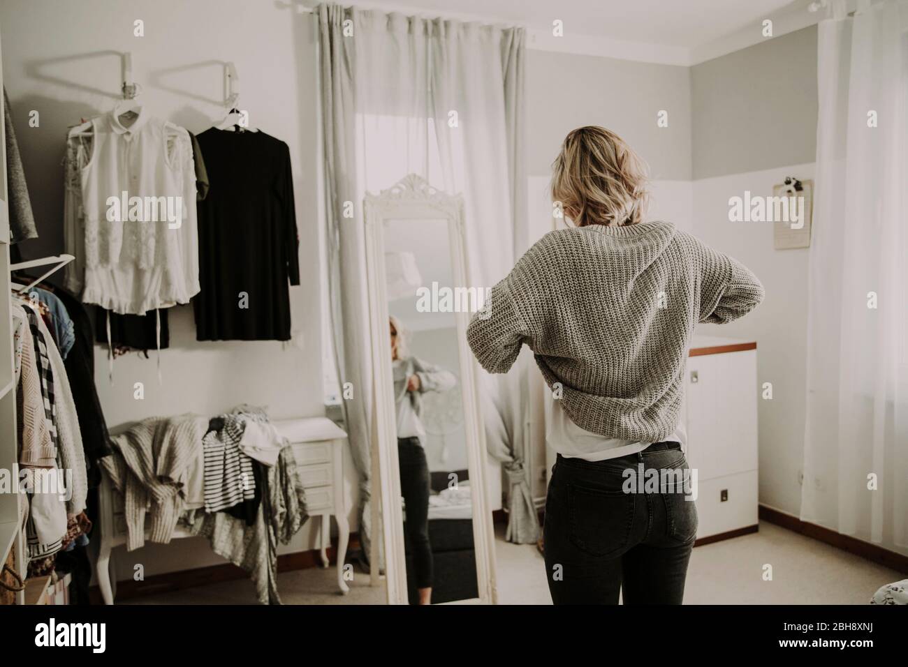 Frau steht vor dem Spiegel, kleidet sich an Stock Photo