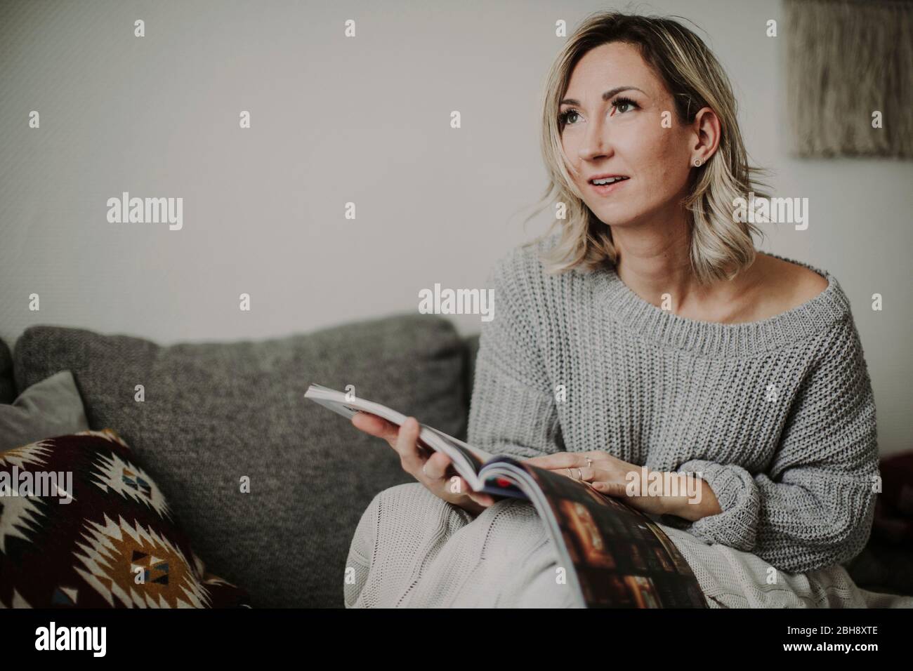 Frau mit Zeitschrift auf der Couch Stock Photo