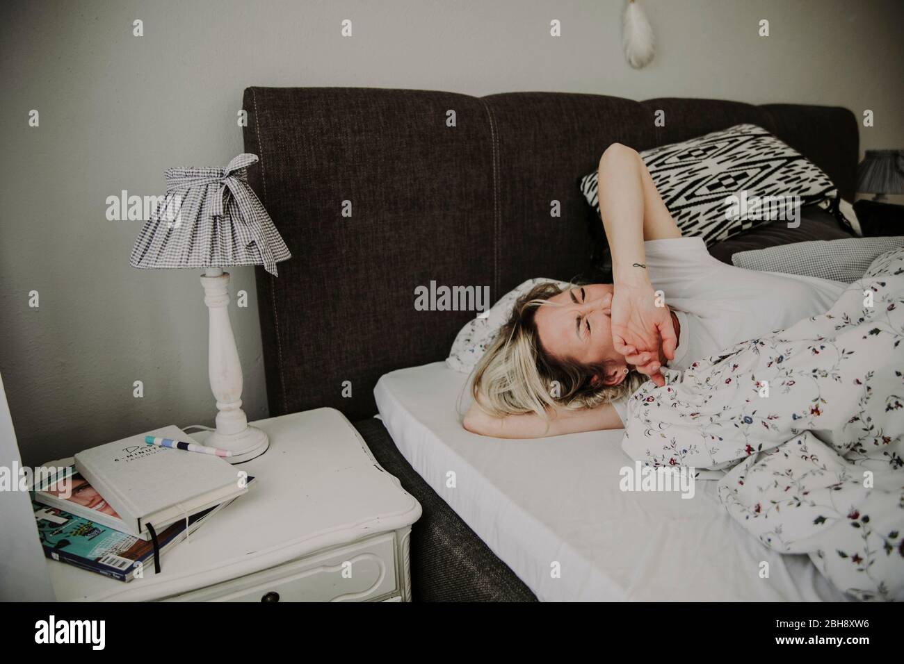 Frau liegt gähnend im Bett Stock Photo