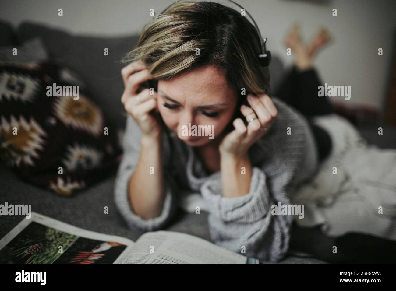 Frau liegt entspannt auf der Couch, Musik hören, Kopfhörer, Illustrierte Stock Photo