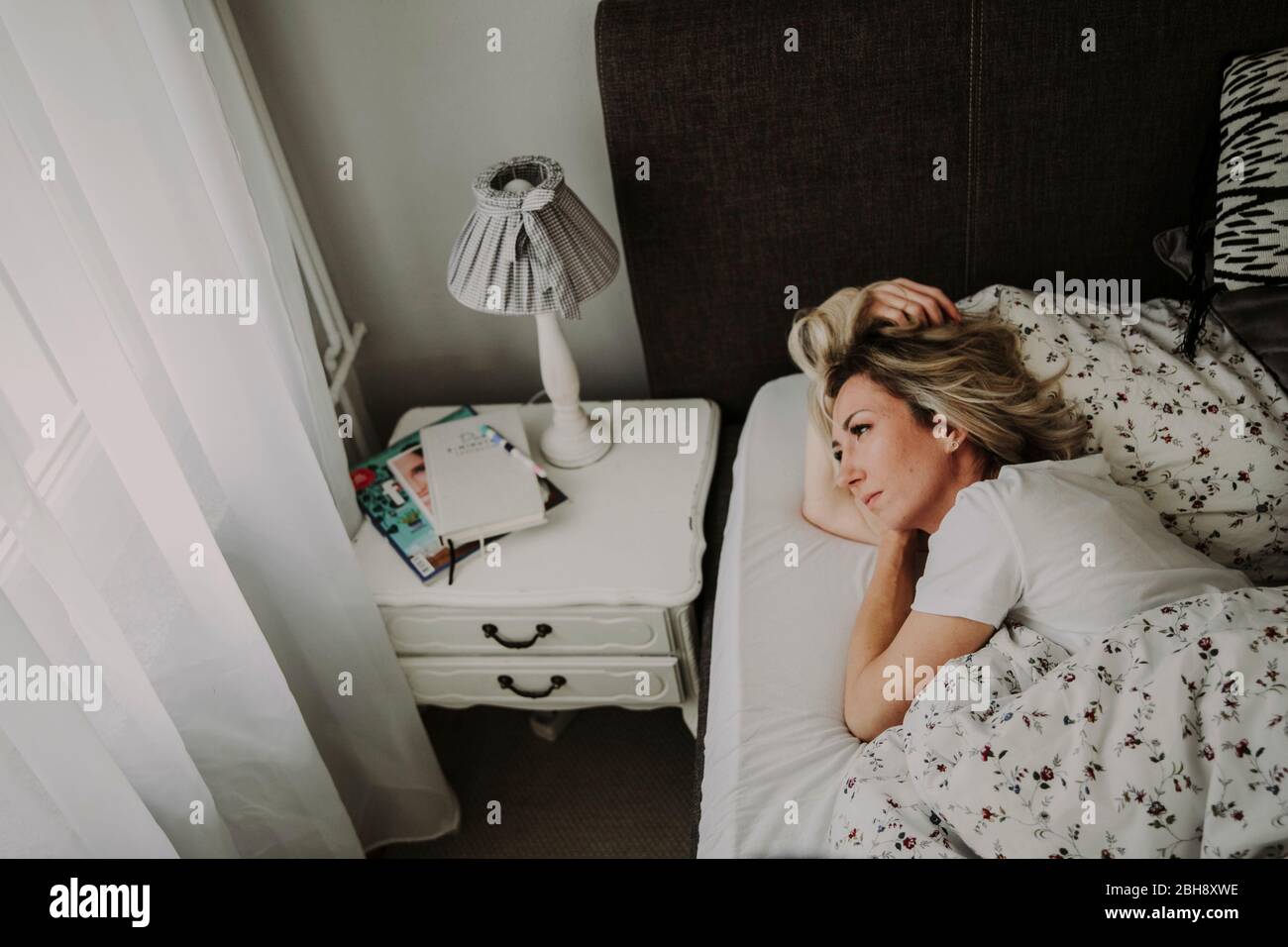 Frau liegt nachdenklich im Bett Stock Photo
