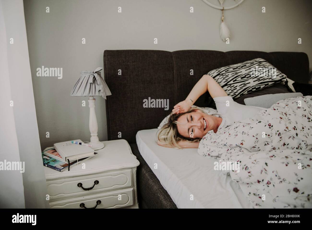Frau liegt lachend im Bett Stock Photo