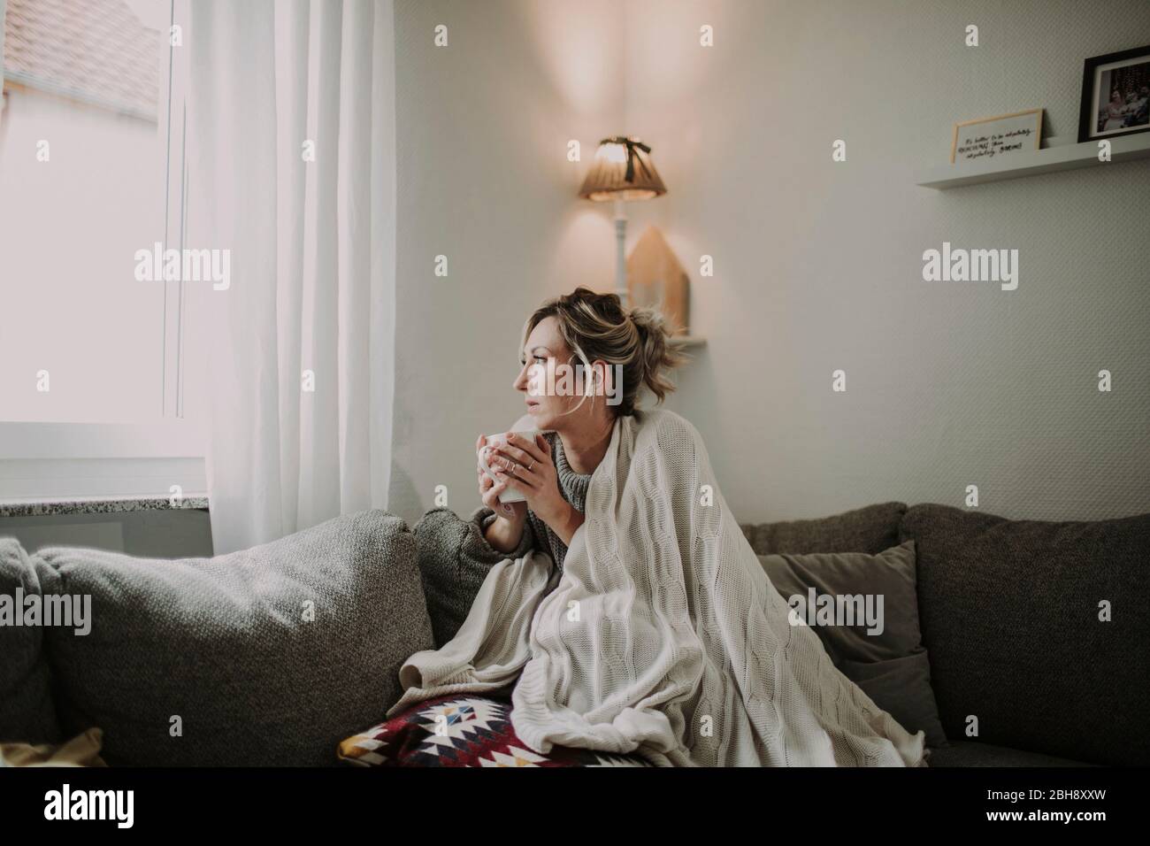 Frau mit Teetasse auf der Couch Stock Photo