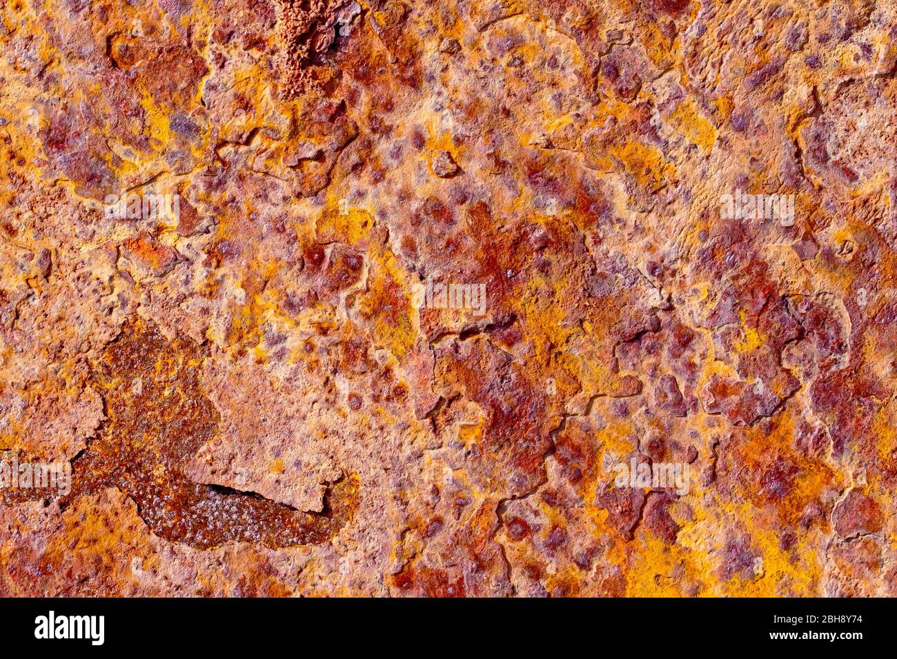 Close up abstract image of the patterns of colour on a sunlit piece of rusty metal. Stock Photo