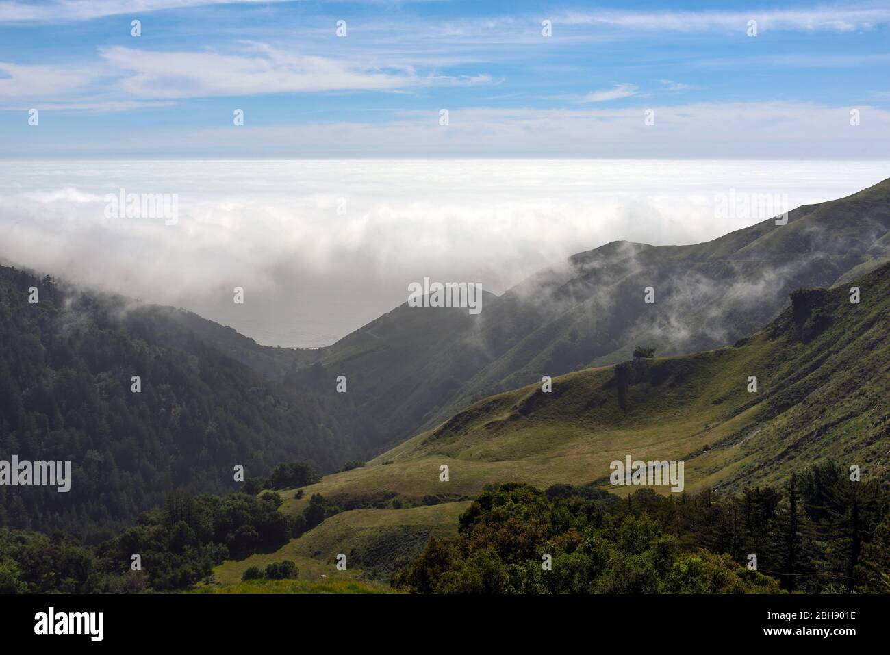 Blick aus den Bergen der Santa Lucia Range um Big Sur zum Pazifik mit tiefhängenden Wolken, grüne Berghänge im Vordergrund Stock Photo