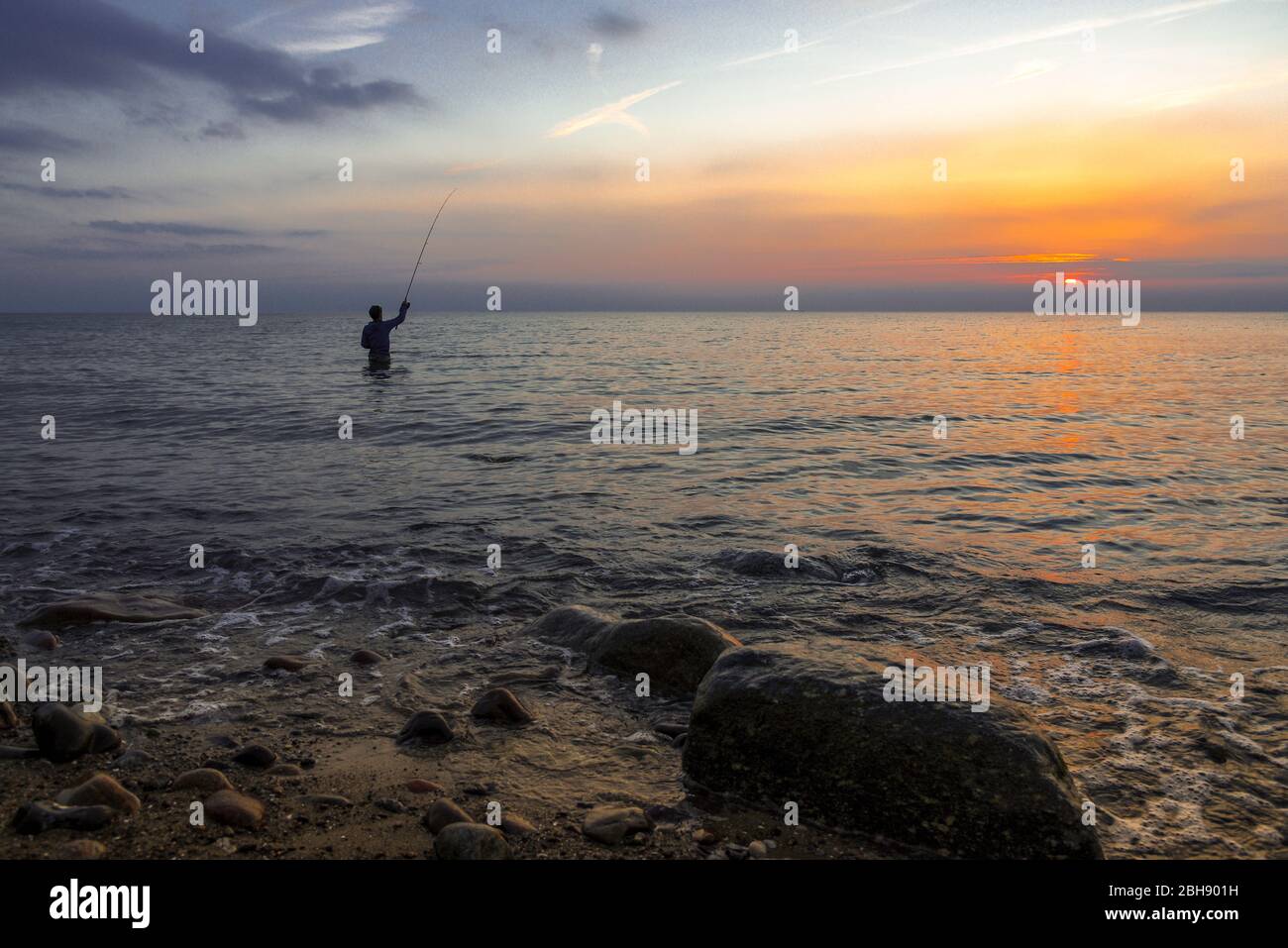 Silhouette eines Anglers in der Ostsee bei Sonnenuntergang Stock Photo