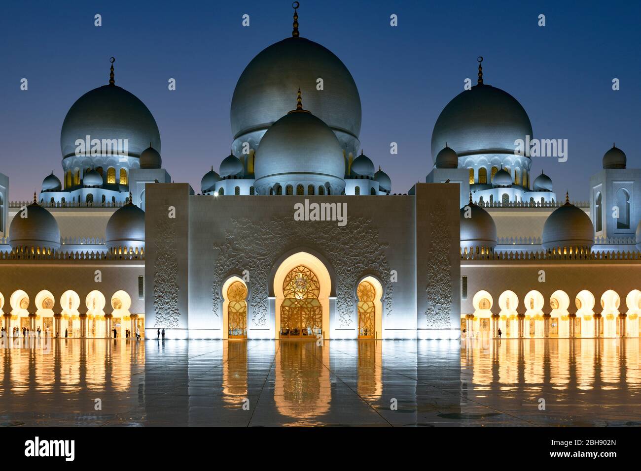 Illuminierte Scheich Zayid Moschee zur blauen Stunde, der Glanz des Marmorbodens kommt besonders gut zur Geltung und lässt die Moschee spiegeln Stock Photo