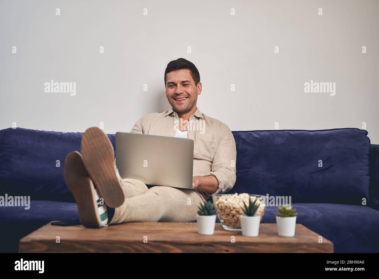 Smiling man with a laptop on his knees Stock Photo - Alamy