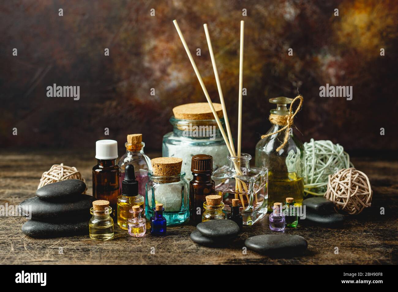 Glass bottles aroma oil and zen stones on wooden table. Spa Treatment Stock Photo