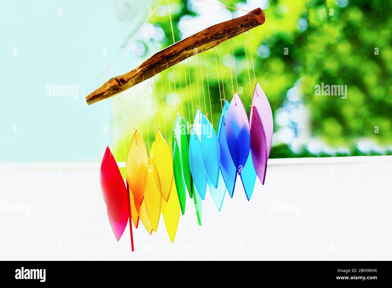 Rainbow glass wind chimes or windchime on nature background. Feng shui symbol. Copy space Stock Photo