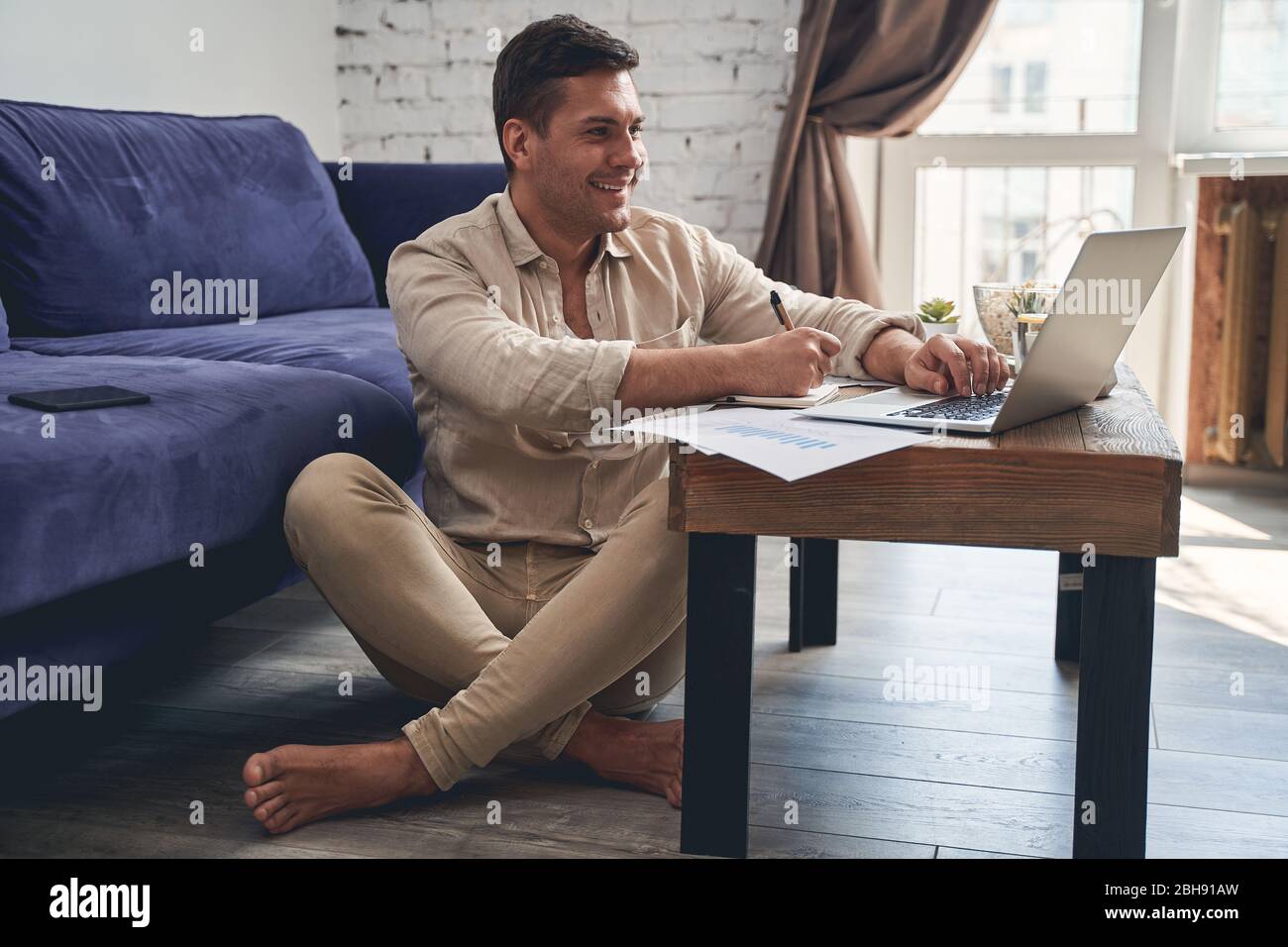 Pleased man sitting crosslegged on the floor Stock Photo Alamy