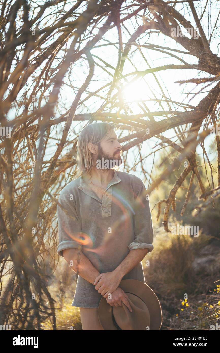 Young man with a beard is looking at the forest on a beautiful sunset in the mountains Stock Photo