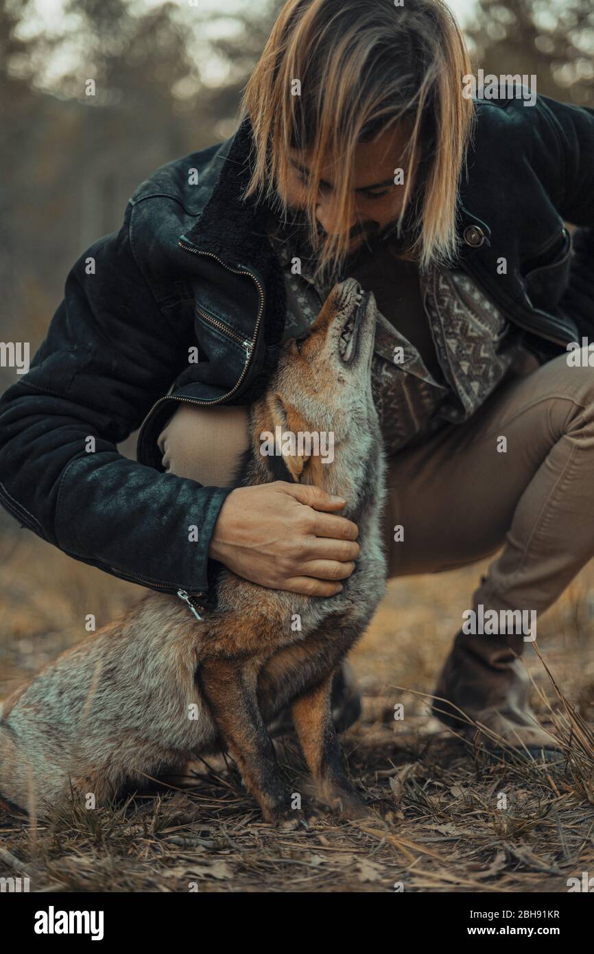 Bearded young man with a wild fox in the mountains Stock Photo