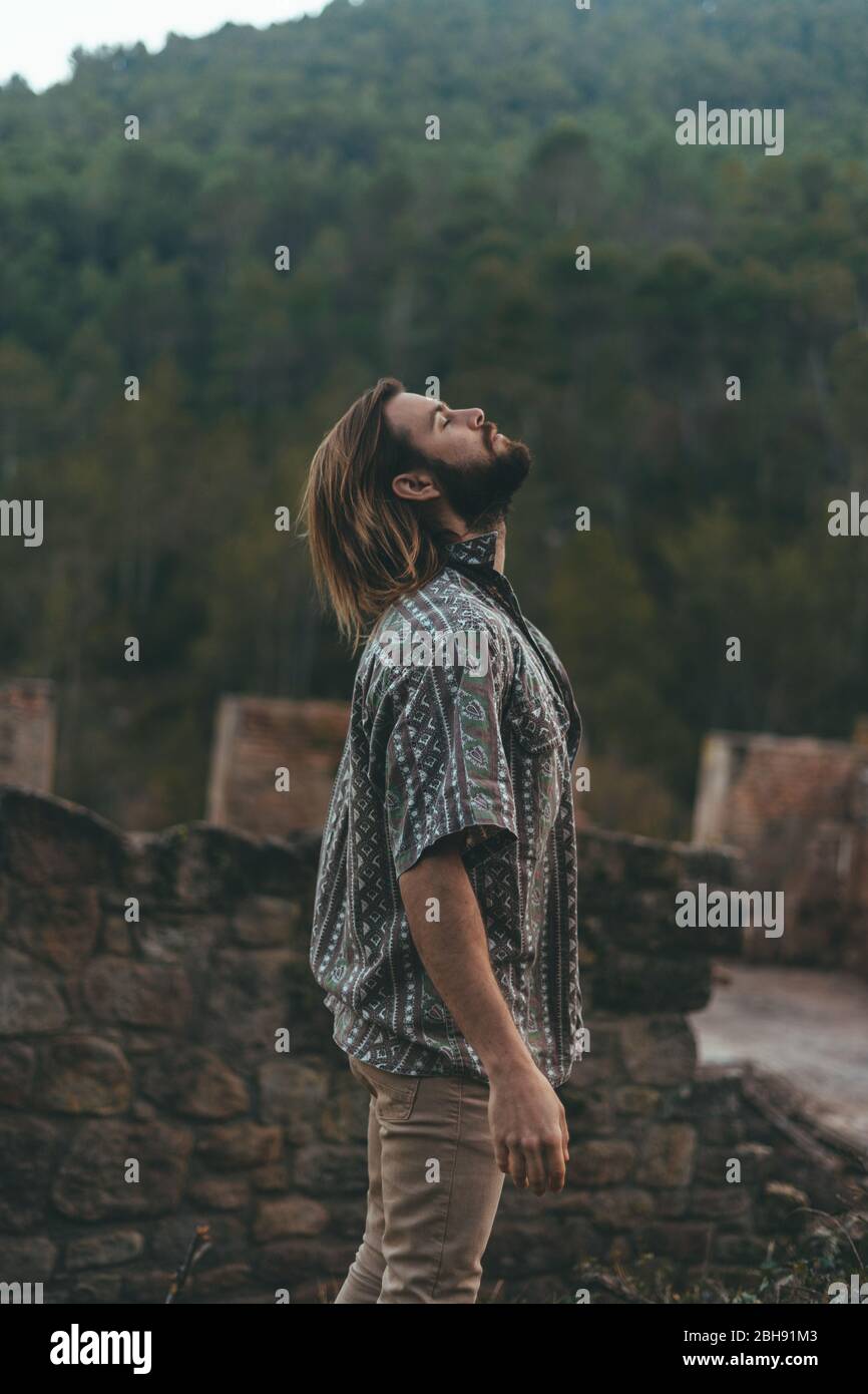 Bearded young man meditating in the middle of the mountain Stock Photo