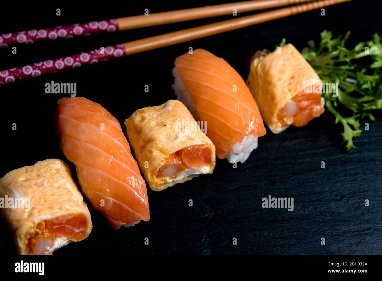 Japanese cuisines nigiri sushi set on black plate served with wasabi, soy sauce. Sushi Roll with salmon, sushi maki roll and tamago sushi on black pla Stock Photo