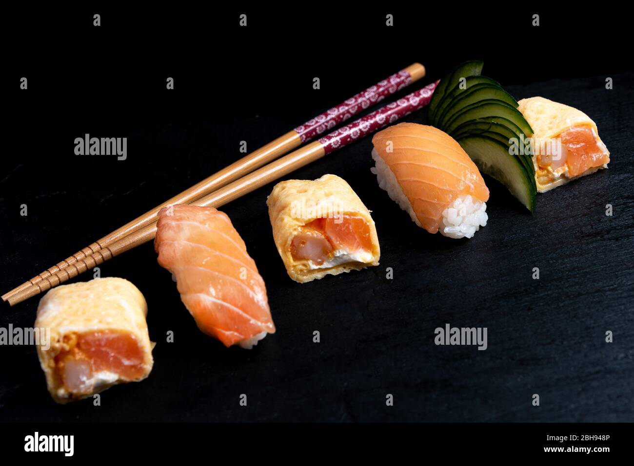Japanese cuisines nigiri sushi set on black plate served with wasabi, soy sauce. Sushi Roll with salmon, sushi maki roll and tamago sushi on black pla Stock Photo