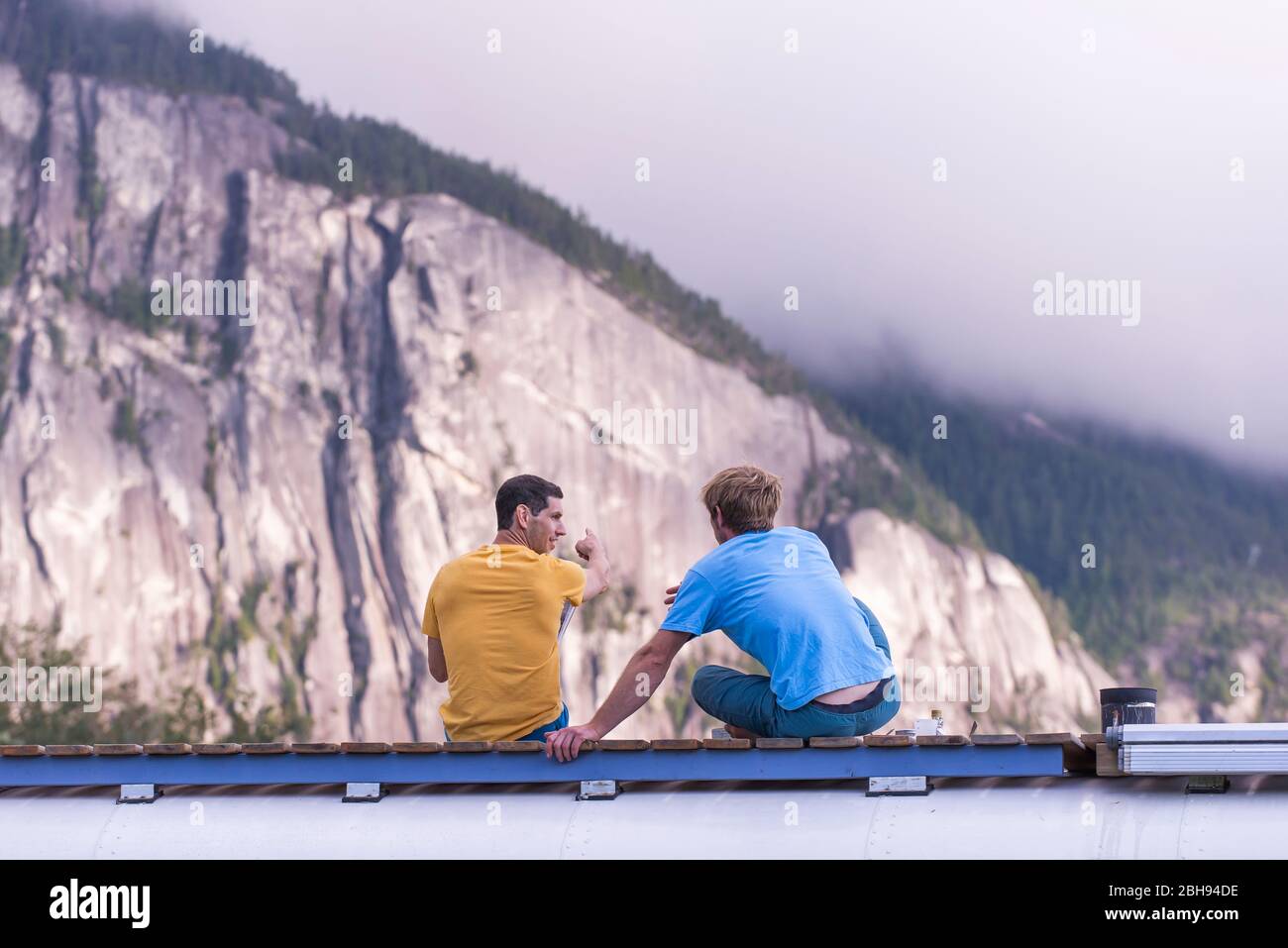 Man pointing out rock climbing cliff with finger on top of school bus Stock Photo