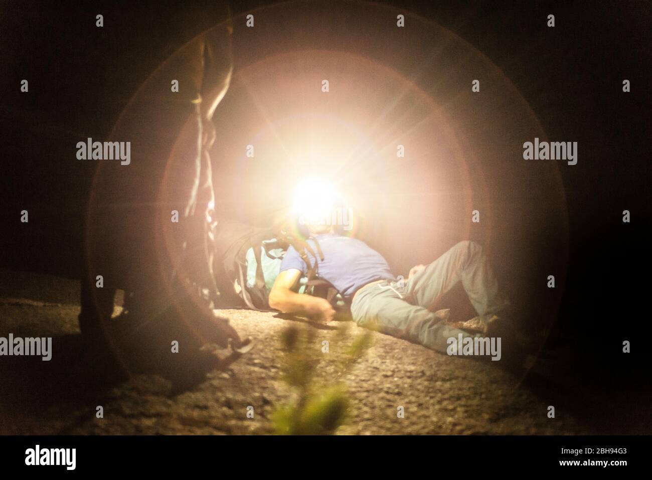 Man laying down with big backpack looking up with headlamp at night Stock Photo