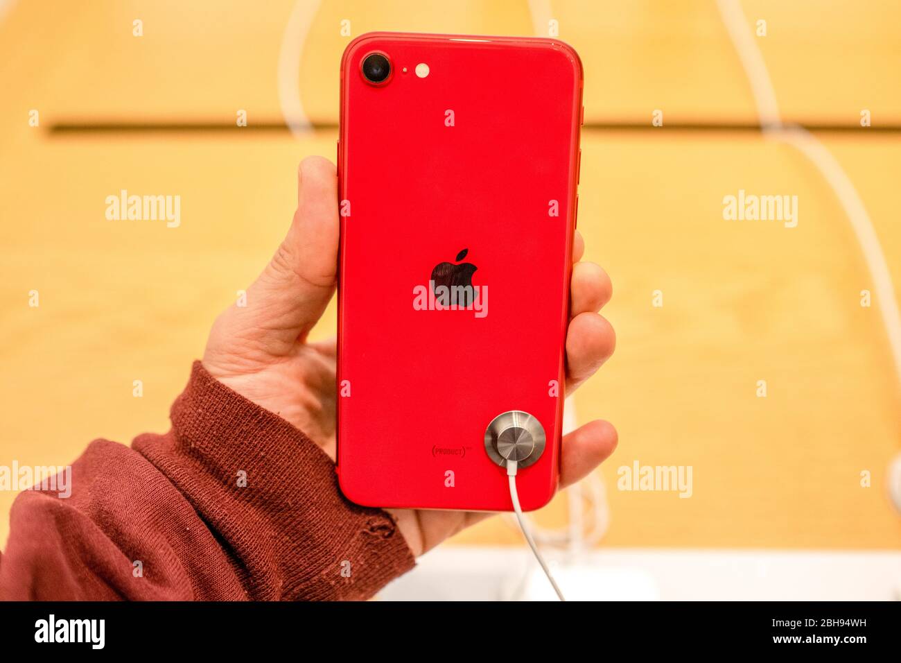 A customer seen holding an iPhone SE (PRODUCT) RED version at an 