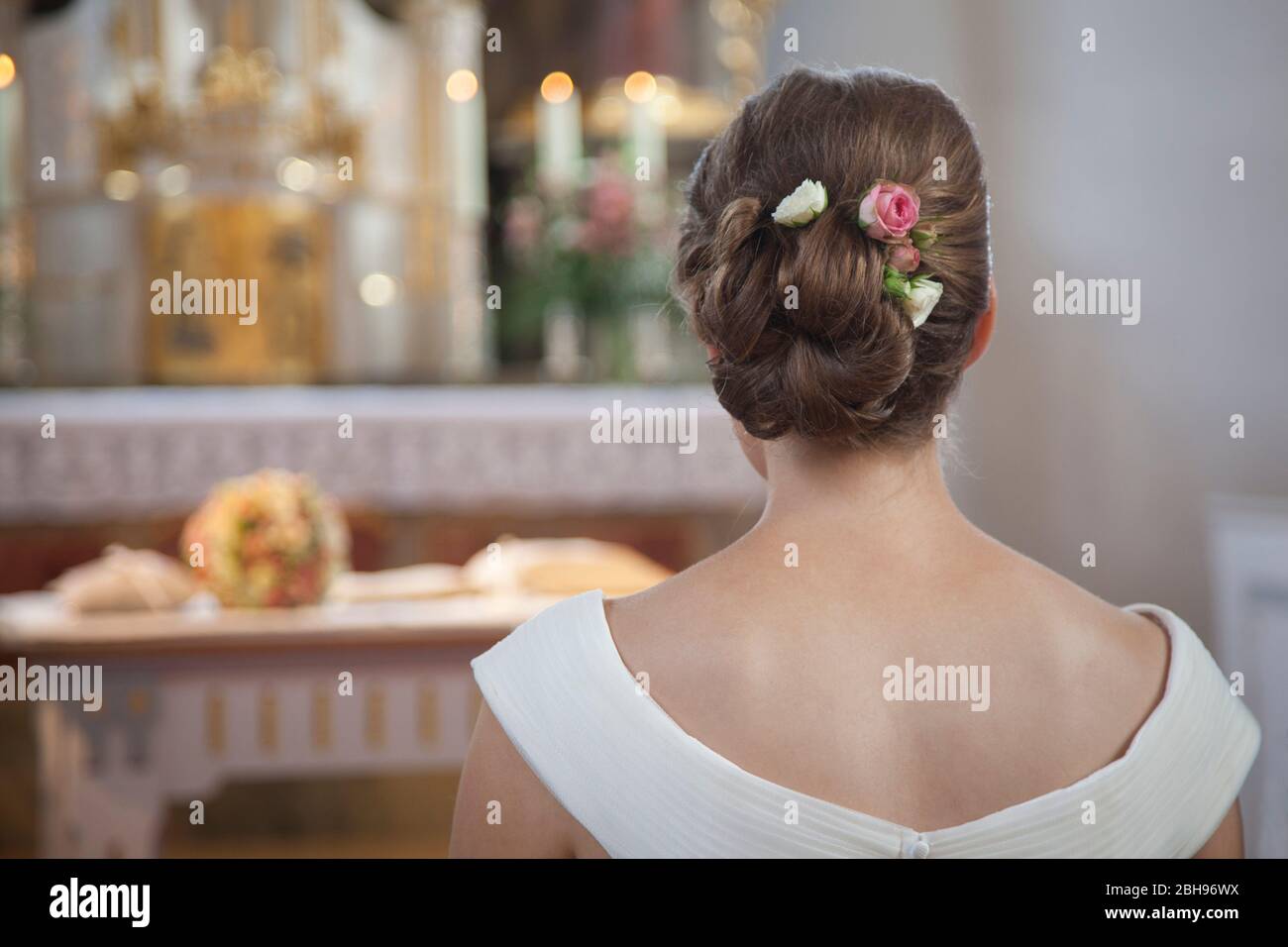 Bride from behind in the church, updo, roses in her hair Stock Photo