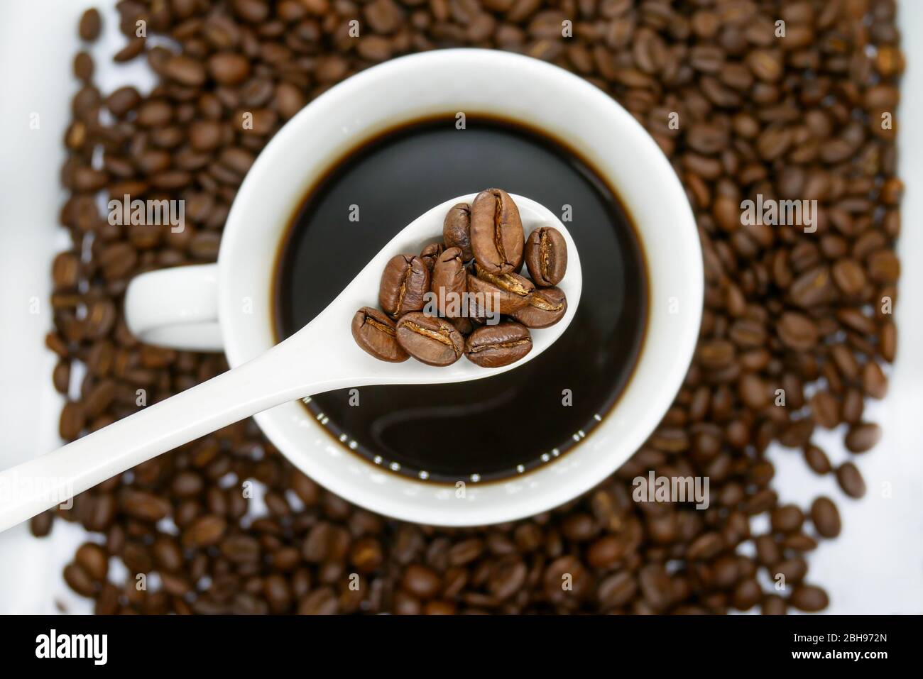 white coffee cup, spoon and roasted coffee beans that isolated on white background. top view. Stock Photo