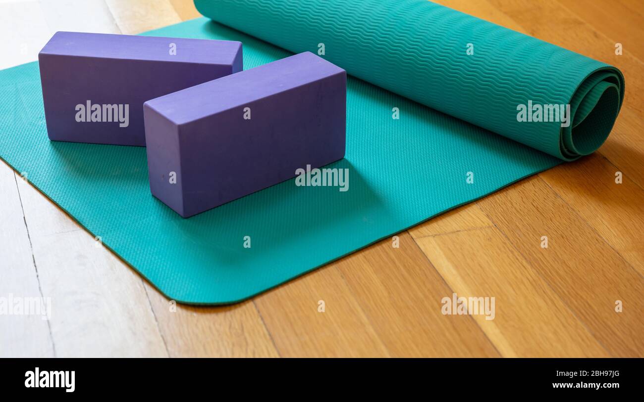 Yoga mat and exercise bricks on wooden floor. Pilates, yoga class, training at home and healthy lifestuyle concept Stock Photo