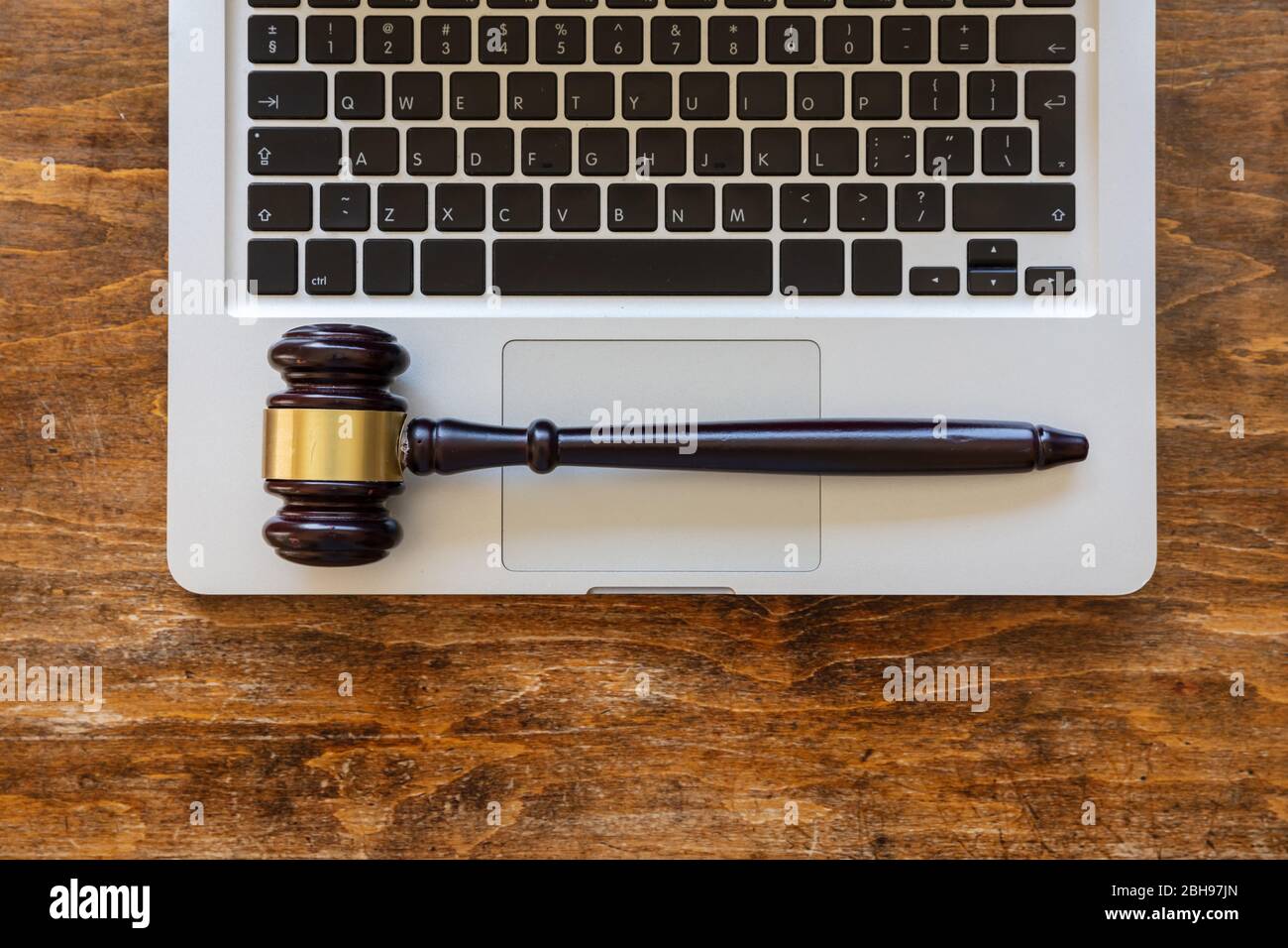 Auction judge gavel on a computer laptop, wooden office desk background, top view. Online auction, legal decisions concept Stock Photo