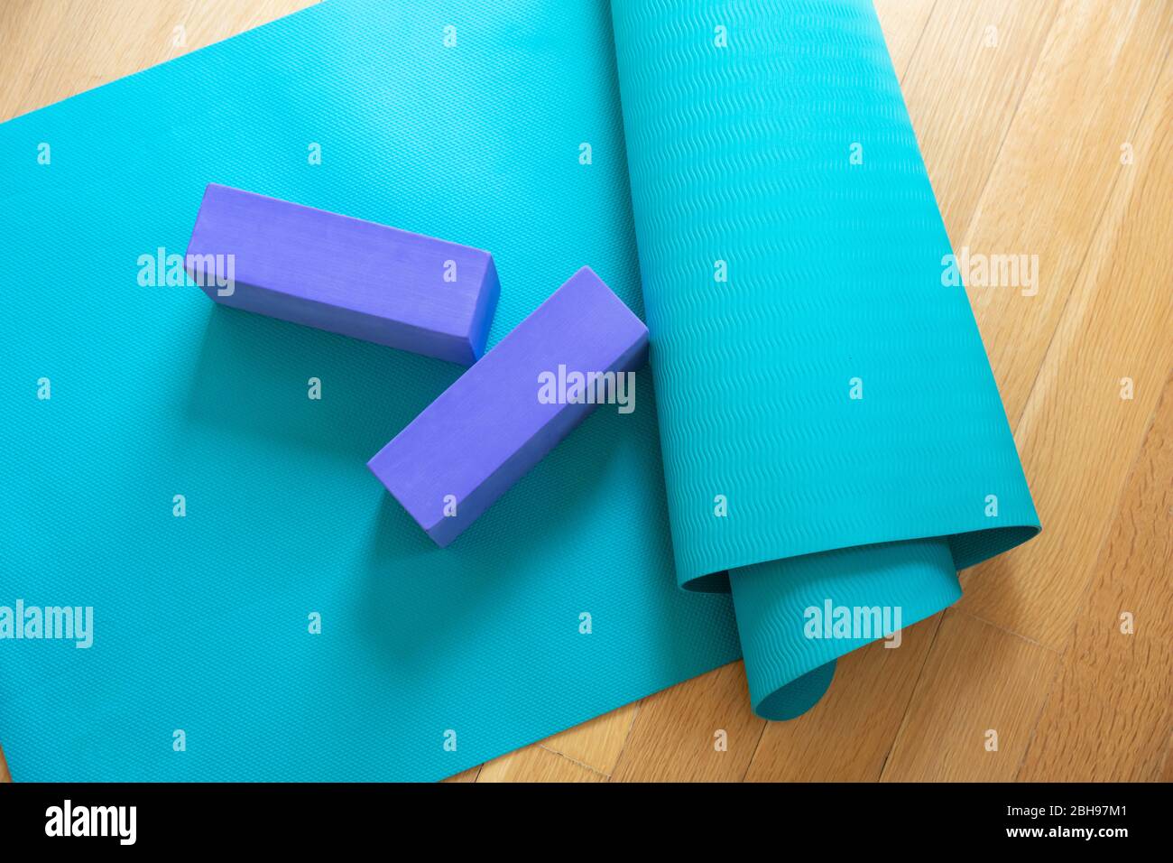 Yoga mat and exercise bricks on wooden floor. Pilates, yoga class, training at home and healthy lifestuyle concept Stock Photo