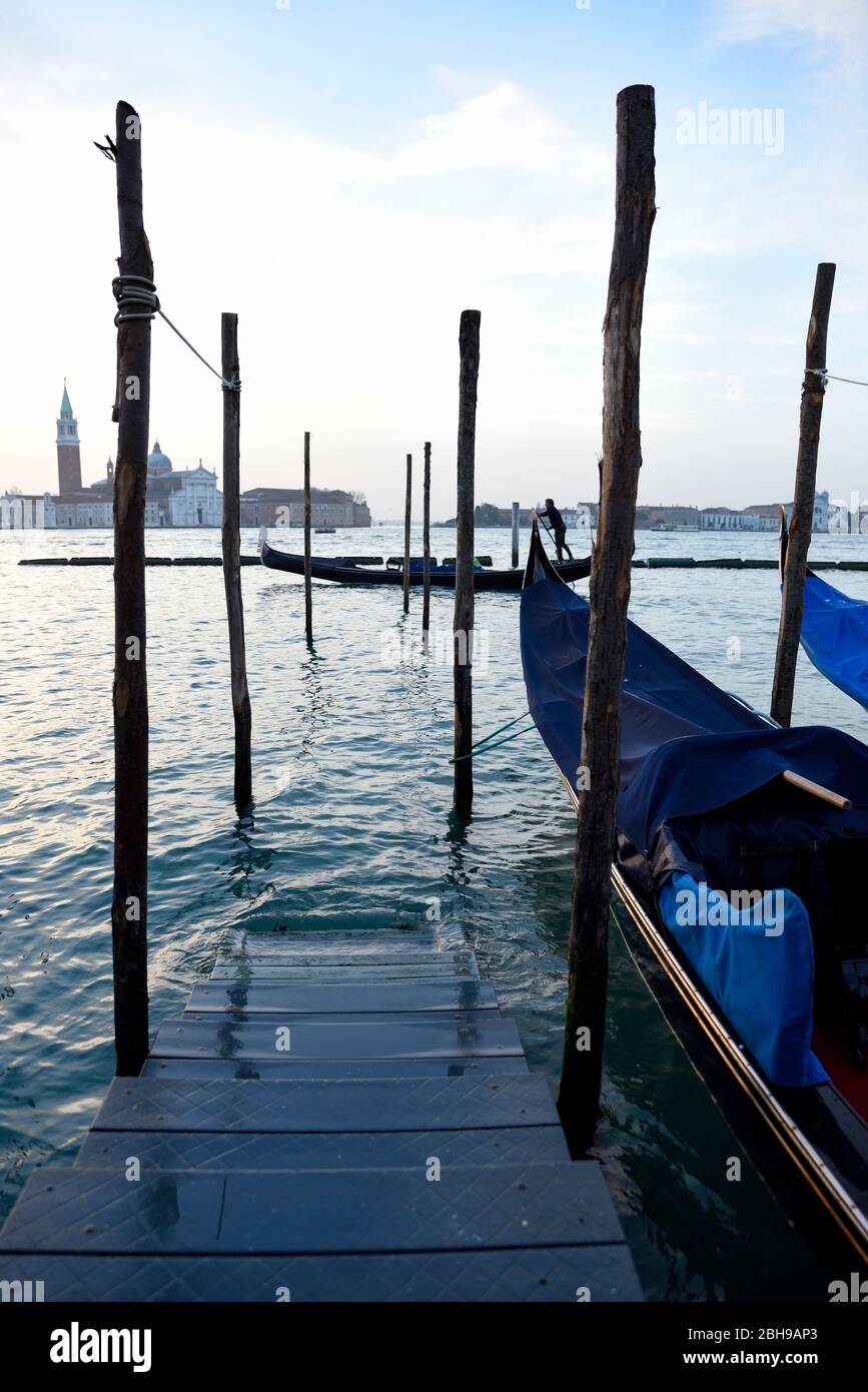 Gondolas and gondoliers on gondola in Venice at sunrise in January am seen from Piazza San Marco -San Giorgio Maggiore in the background Stock Photo