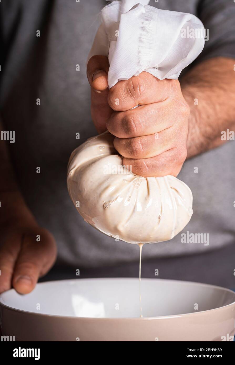 Man making horchata, squeezing almonds and rice paste. Horchata is a mexican traditional drink made up of rice and almonds soaked in milk, flavored wi Stock Photo