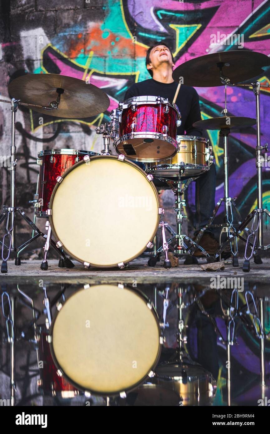 Young man playing drums in an underground environment Stock Photo