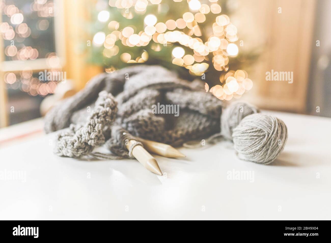Gemütliches Weihnachten mit schöner Beleuchtung und dem Strickzeug mit großen Nadeln und schöner Wolle. Stock Photo