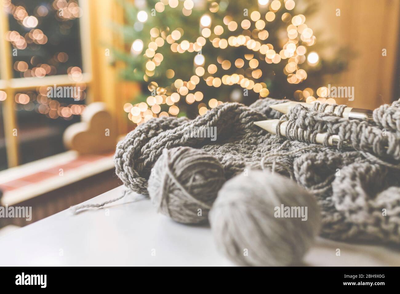 Gemütliches Weihnachten mit schöner Beleuchtung und dem Strickzeug mit großen Nadeln und schöner Wolle. Stock Photo