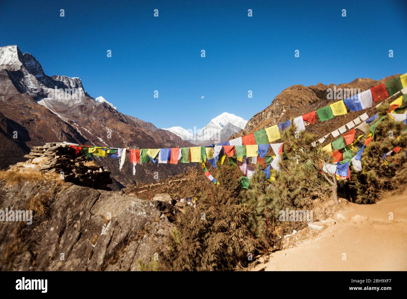 Prayer flag and cairn in the foreground, mountains in the background Stock Photo