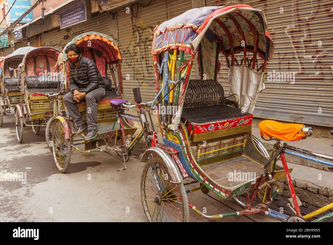 Rickshaws at the roadside with chauffeur, Kathmandu, a young man waiting for customers Stock Photo
