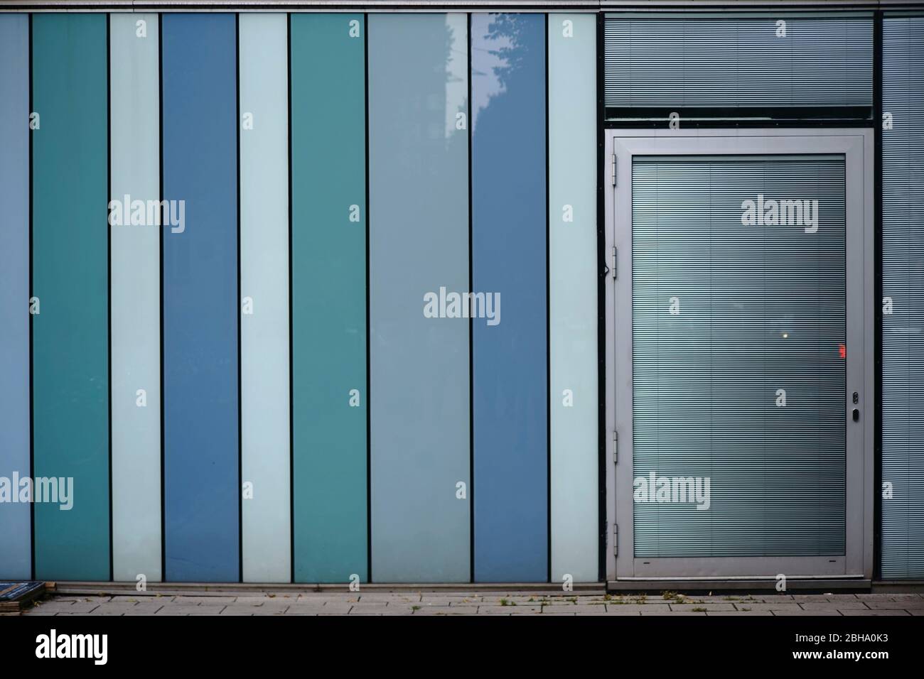 A modern house facade made of plastic panels with a door and metal blinds. Stock Photo