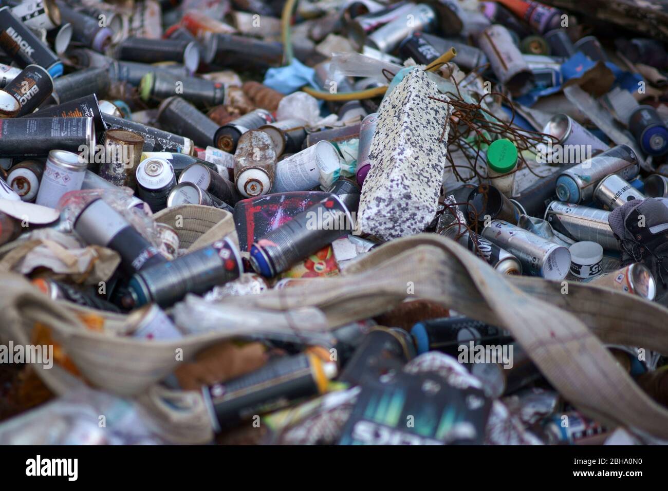 Empty spray cans of graffiti sprayers lie carelessly stacked on top of each other. Stock Photo