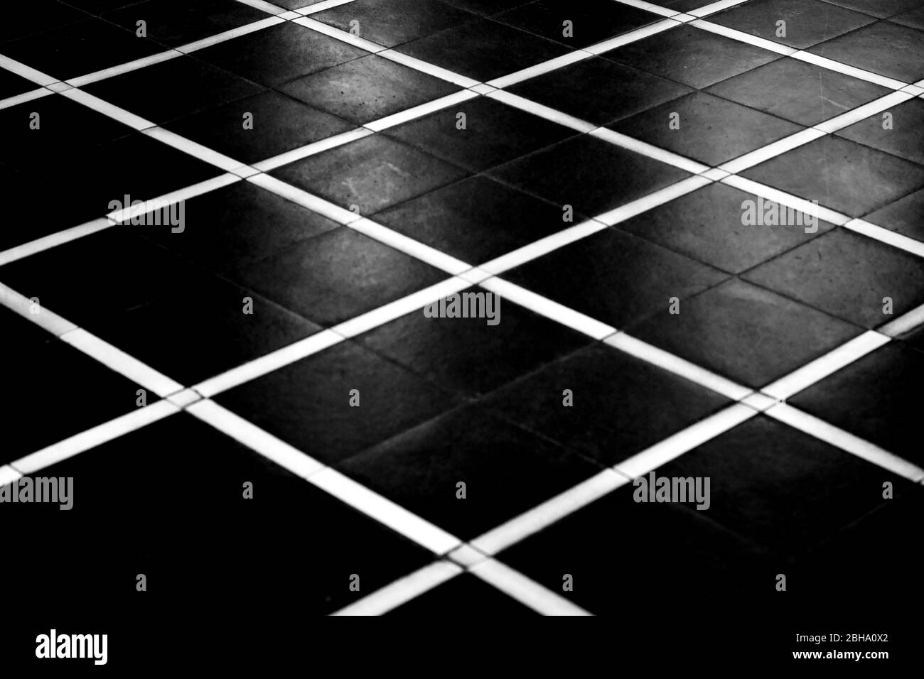 The high contrast top view of the geometrically arranged floor panels of a lobby in black and white pattern. Stock Photo