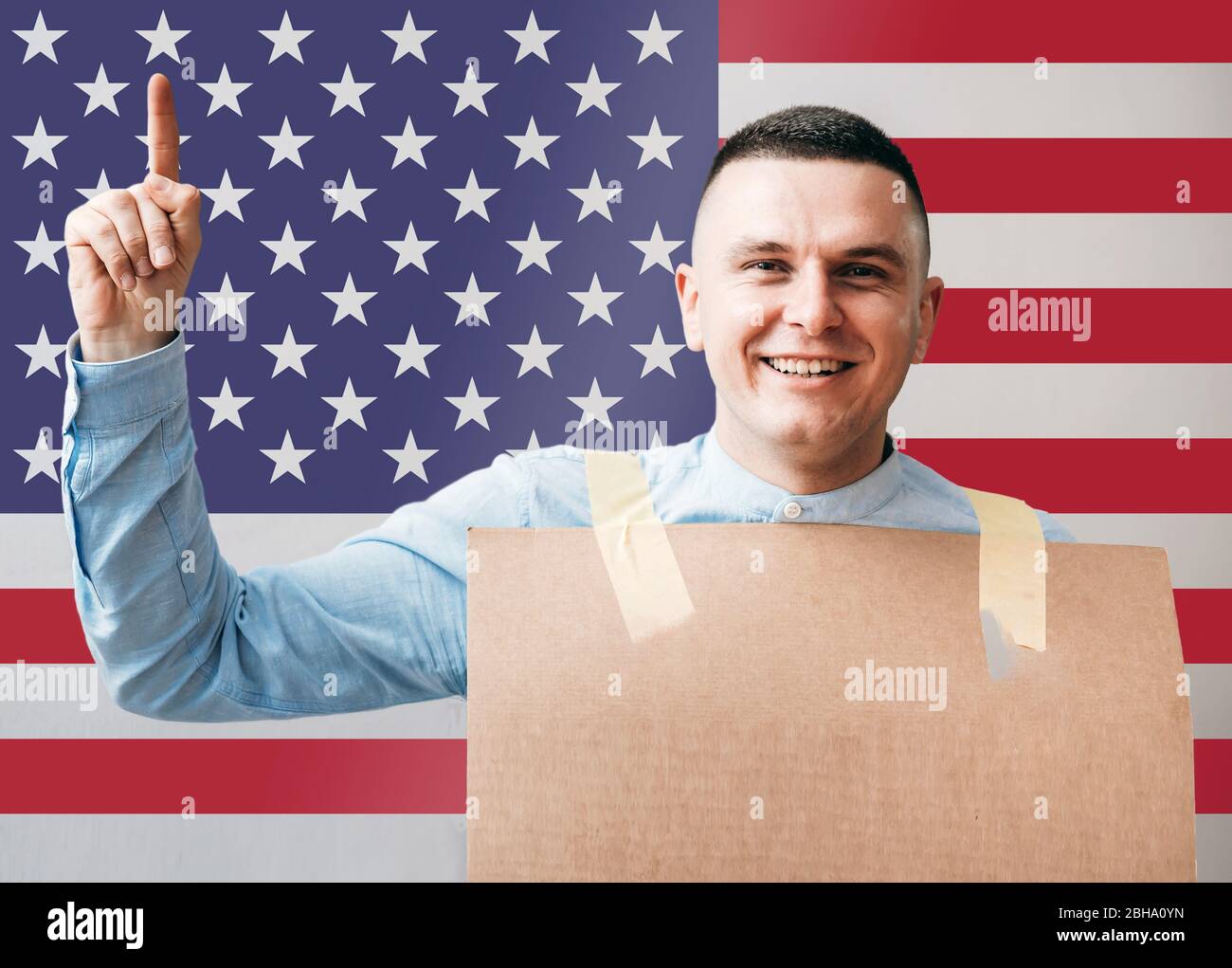 Man with arm raised holding sign with mock-up American flag in background Stock Photo