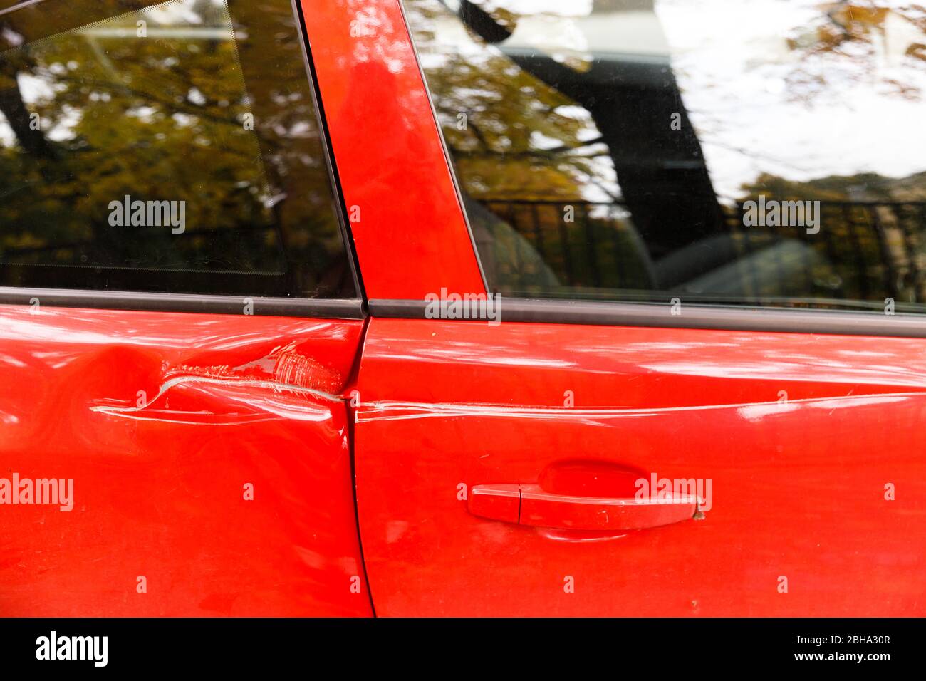 Door red car damaged in a deep dent accident, scratches on the doors. Car repair concept. Stock Photo